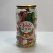 Clear Christmas lolly can with gold lid and festive “Jingle All the Way” label, filled with red, green and white lollies, wrapped mints and chocolates.