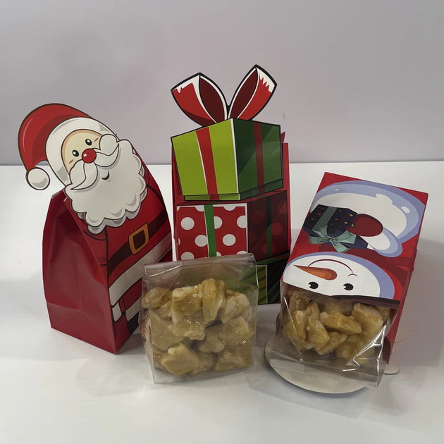 Assorted Christmas gift bags with Santa, snowman and present designs, showing individually packaged pieces of golden macadamia brittle.