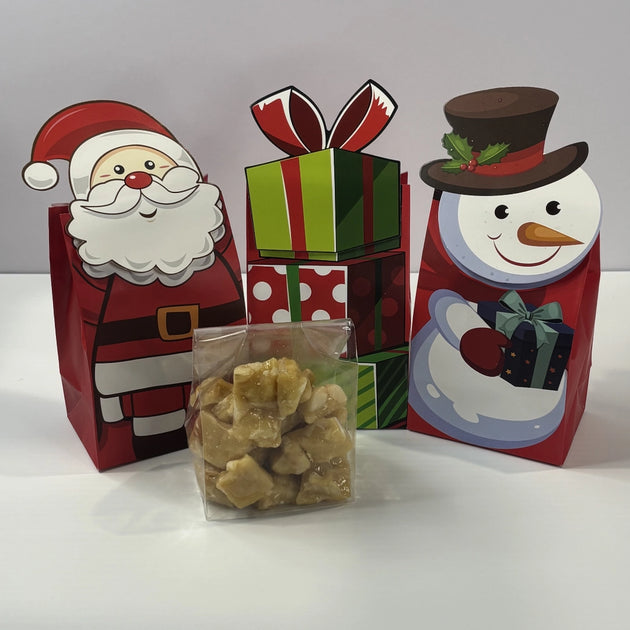 Christmas macadamia brittle gift bags featuring Santa, a snowman and festive presents, with a clear bag of golden macadamia brittle displayed in front.