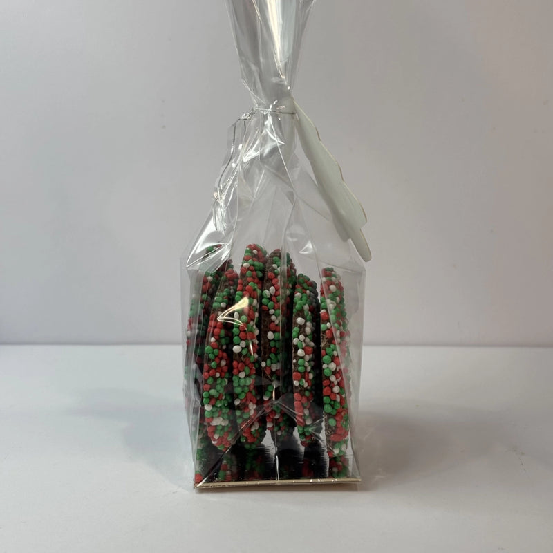 Side view of clear gift bag filled with round milk chocolate Christmas speckles covered in red, green and white sprinkles, finished with a Merry Christmas tree-shaped gift tag.