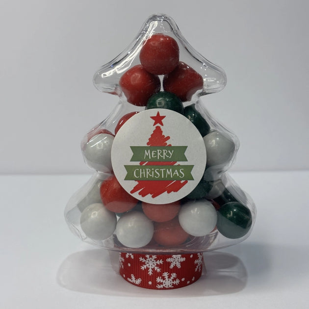 Clear Christmas tree-shaped container filled with red, green and white candy-coated peppermint chocolate balls and Jaffas. Container features a Merry Christmas sticker on the front. 