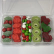 A clear plastic compartment box filled with assorted Christmas themed snack box filled with assorted red, green and white lollies and chocolates, including spearmint leaves, Jaffas, strawberry clouds, chocolate buttons, apple rings and frogs.