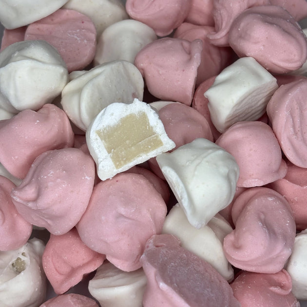 Pink and white frosted caramels with one cut open to show the chewy caramel centre