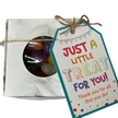 A square gift box with a circular window showing colourful jelly beans inside, tied with string and a gift tag that reads 'JUST A LITTLE TREAT FOR FOR YOU!'