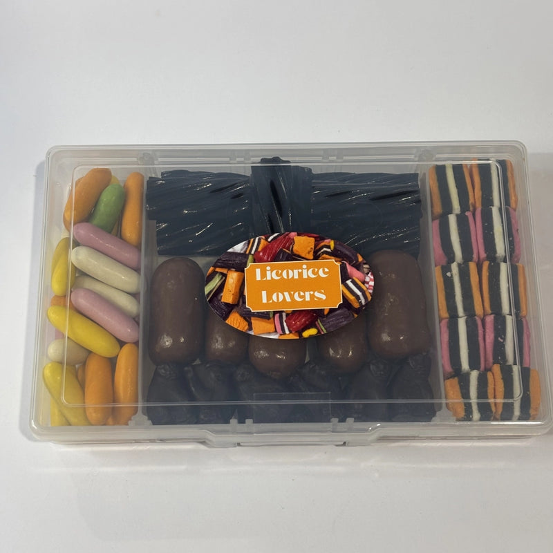 Clear compartment-style snack box filled with assorted licorice confectionery, including colourful candy licorice bullets, black licorice twists, jumbo milk chocolate bullets, Black Cats and striped licorice allsorts.