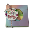 A square gift box with a circular window showing rainbow marshmallows, tied with string and a 'Happy Birthday' gift tag.