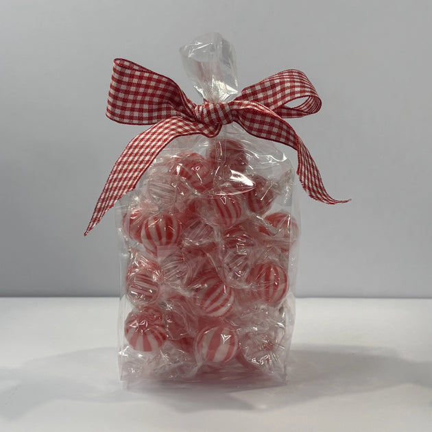 Clear gift bag filled with individually wrapped red and white striped mint baubles, finished with a red and white gingham ribbon bow