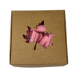 A square gift box with a leaf-shaped cutout on the lid, revealing pink mini musk sticks inside.