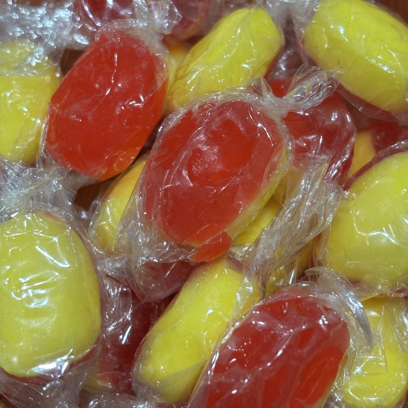 Individually wrapped hard yellow and red candy with a rhubarb and custard filling