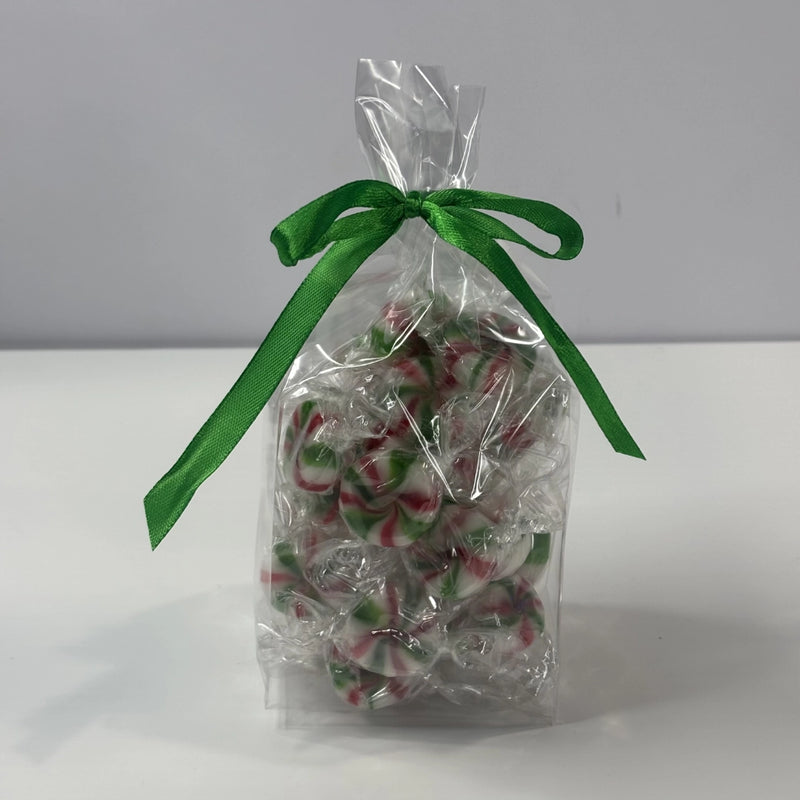 Clear gift bag filled with individually wrapped red, green and white Starlight Mints, tied with a ribbon.