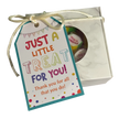 A square gift box with a round window showing Thank You rock candy inside, tied with a ribbon and a gift tag that reads 'JUST A LITTLE TREAT FOR YOU! Thank you for all that you do!"