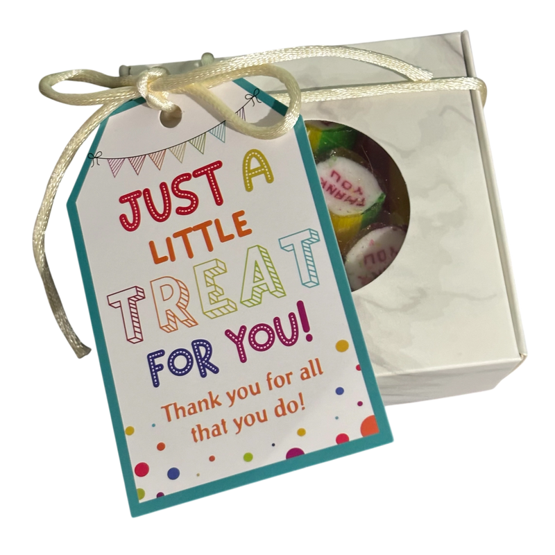 A square gift box with a round window showing Thank You rock candy inside, tied with a ribbon and a gift tag that reads 'JUST A LITTLE TREAT FOR YOU! Thank you for all that you do!"