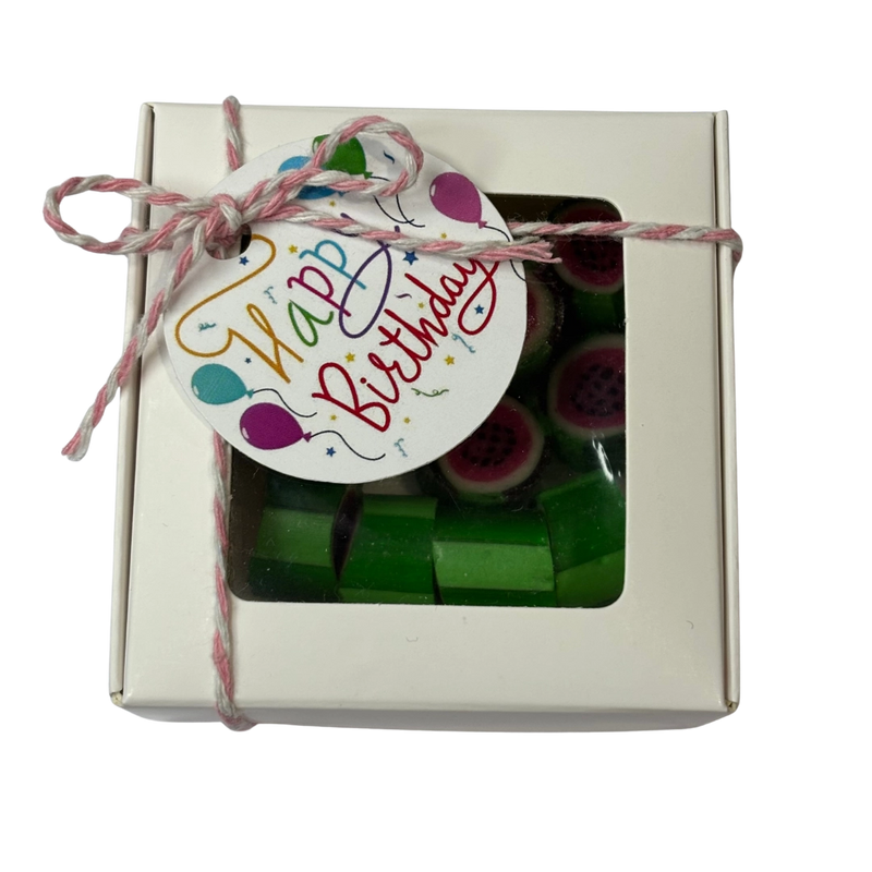 A square gift box containing green and pink watermelon rock candy inside, tied with a string and a 'Happy Birthday' gift tag.