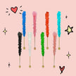 Colorful rock candy sticks in various shades including blue, pink, red, turquoise, green, and black, arranged on a light pink background.